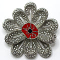 A silver and green brooch with a red poppy flower center, adorned with small silver stones and a central red poppy flower.
