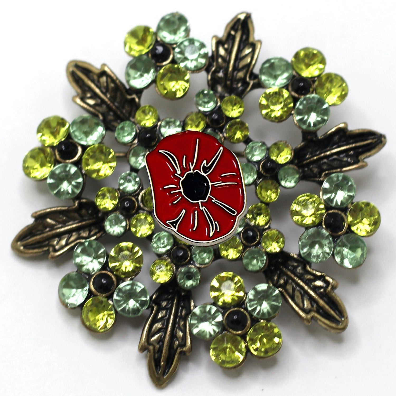 A brooch with a red poppy flower centerpiece surrounded by green and silver accents