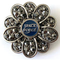 A brooch with a 'Space Force' centerpiece and crystal rhinestones, featuring a floral-like design.