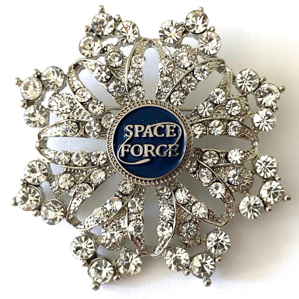 A brooch with a central Space Force emblem surrounded by crystal rhinestones on a shield-shaped background.