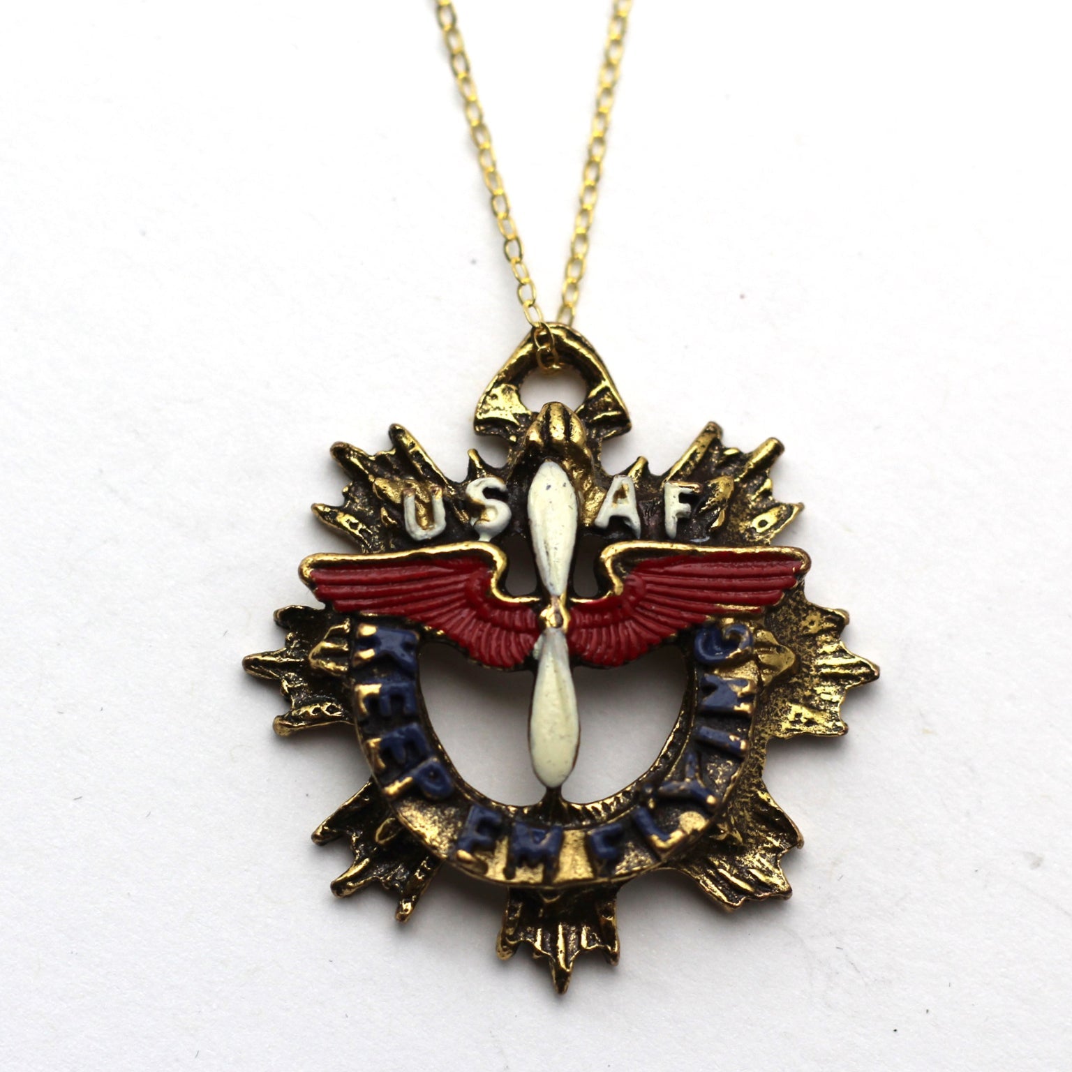A vintage WWII-era sweetheart necklace with a gold-filled chain and a red, blue, and gold colored pendant featuring an aviation 'keep em flying' charm, and the USAF logo.