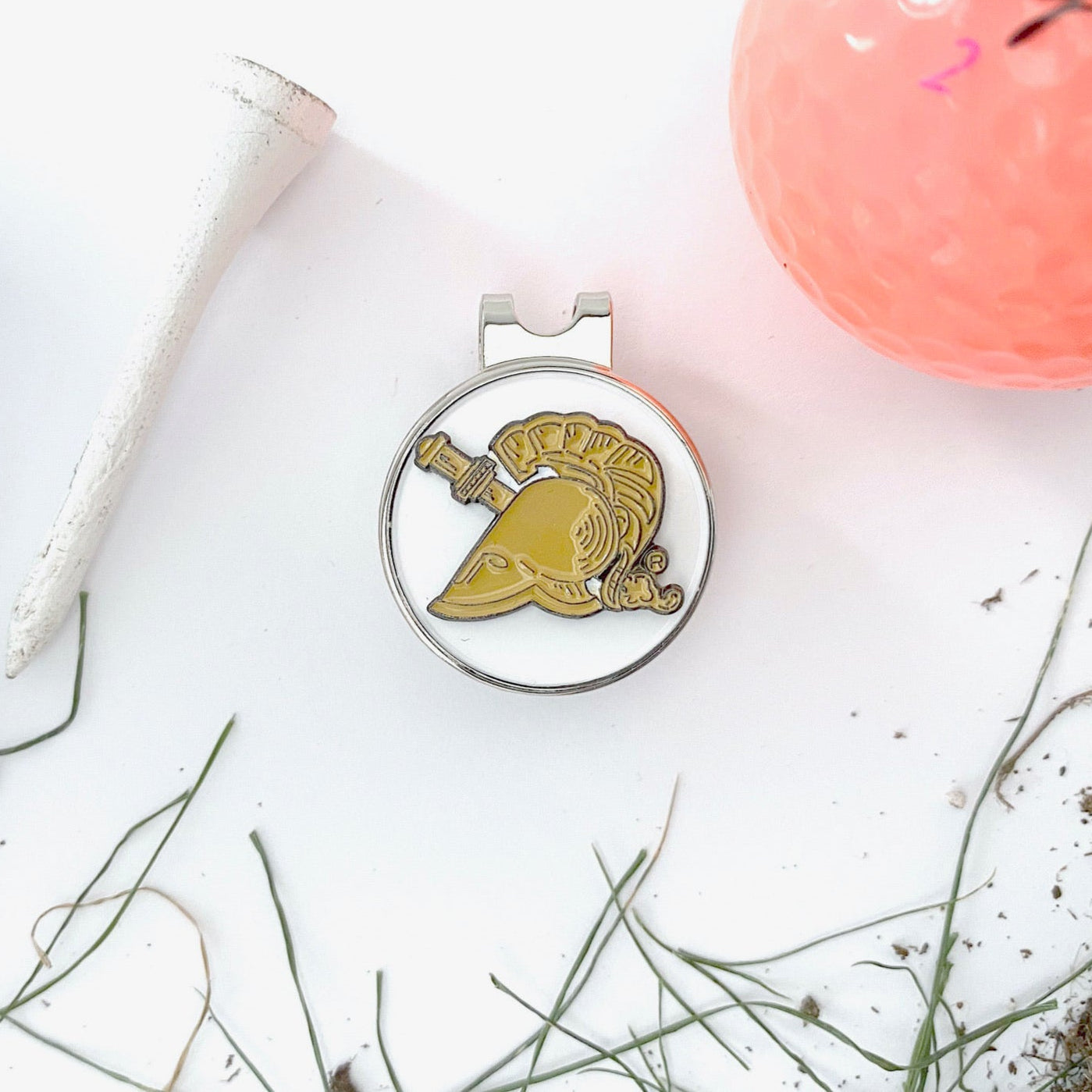 Golf accessories including a ball, tee, and marker with a logo on a white surface.