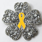 Decorative brooch with a yellow ribbon and crystal-like design on a white background